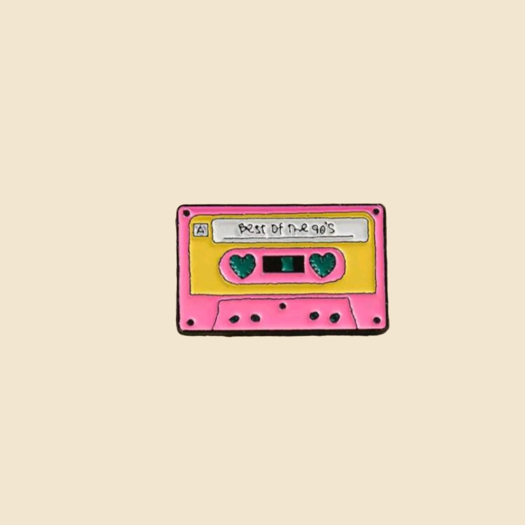 Cassette tape-shaped pin with a yellow label on a stone surface